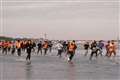 Migrants run across beach to board dinghy in the Channel