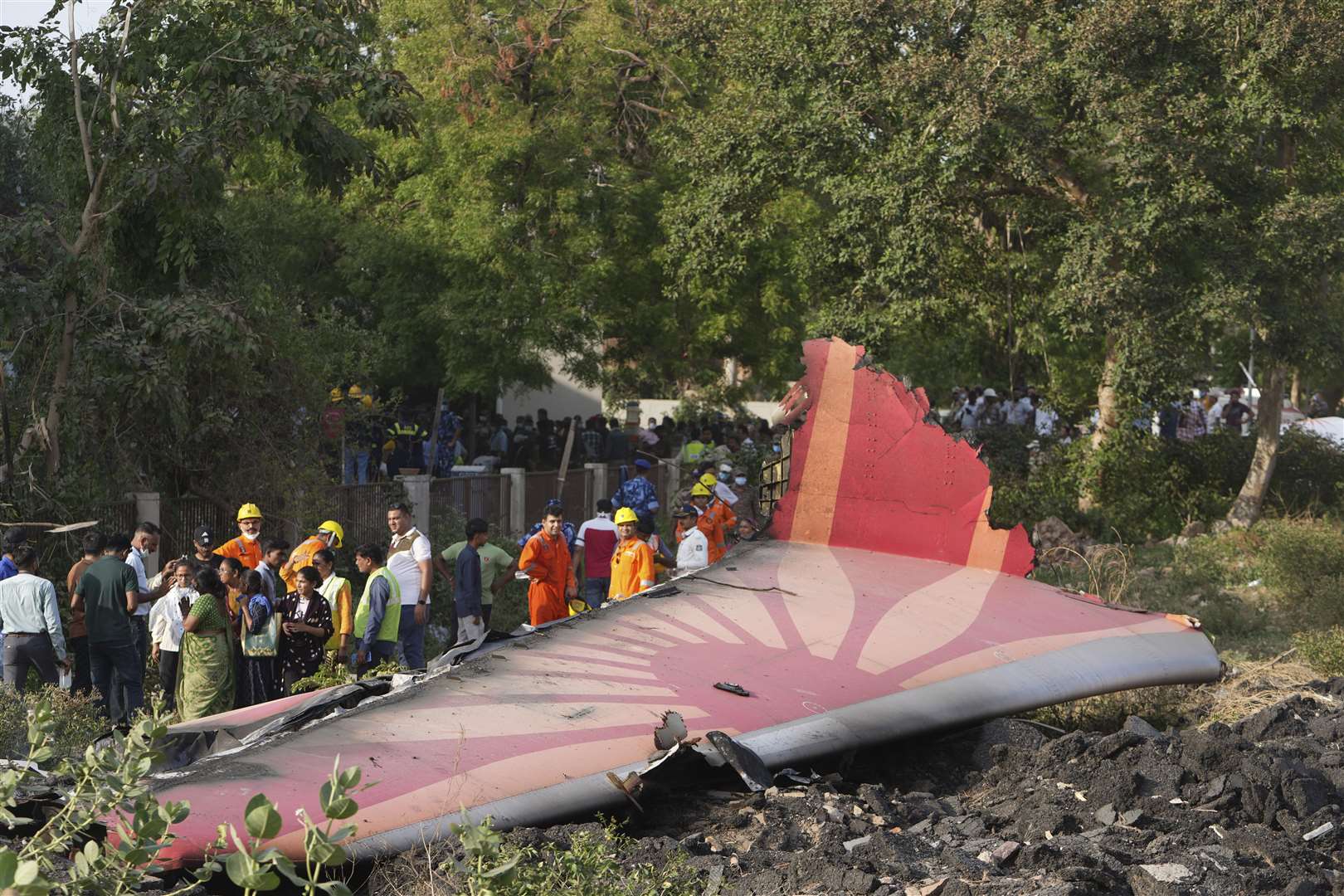 People stand around the debris of the plane (Ajit Solanki/AP)