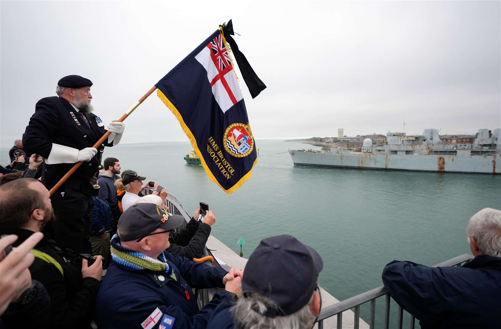 Dick Shenton of the HMS Bristol Association holds up a flag as HMS Bristol leaves Portsmouth harbour (Andrew Matthews)