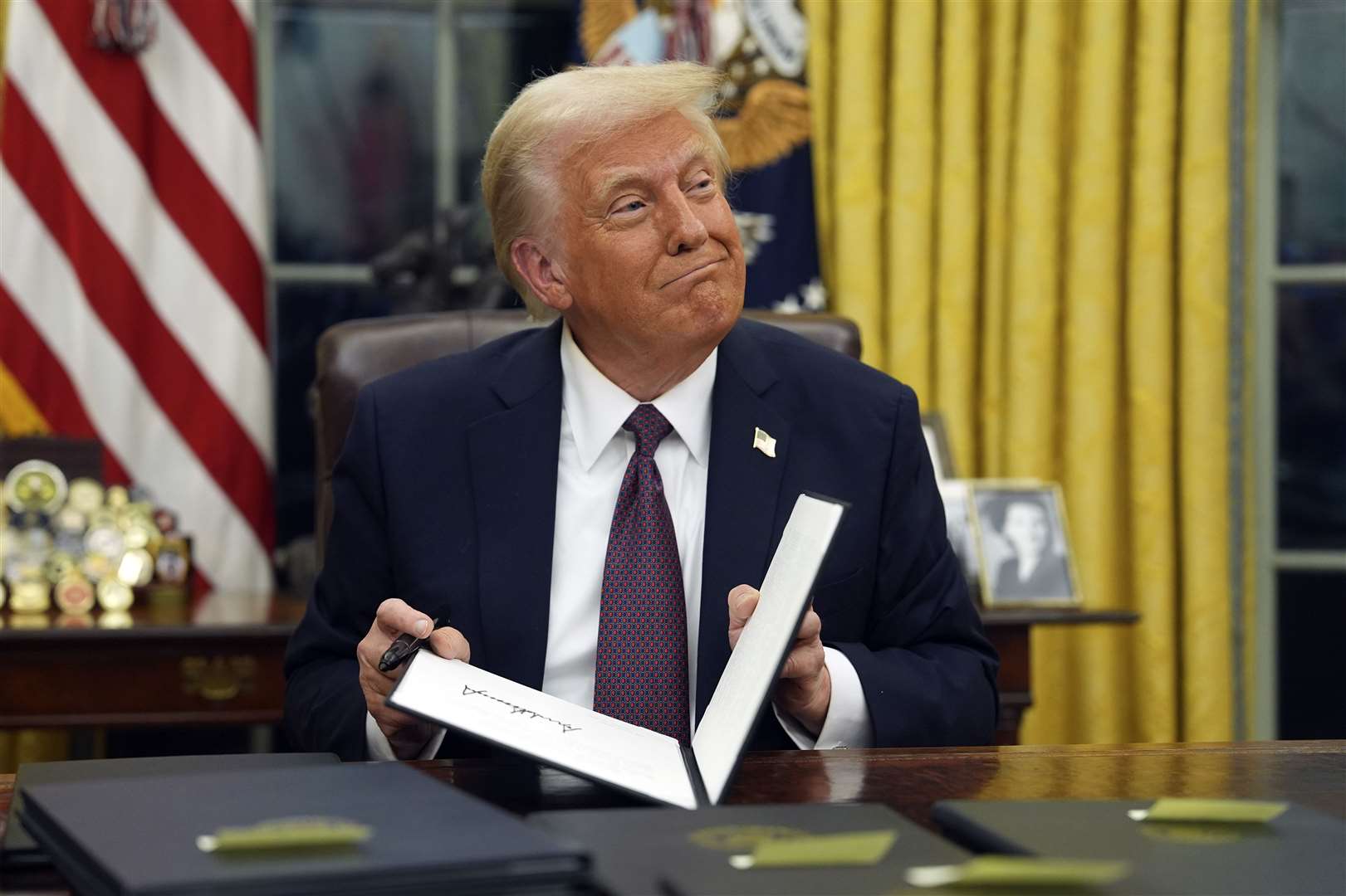 President Donald Trump signs executive orders in the Oval Office (Evan Vucci/AP)