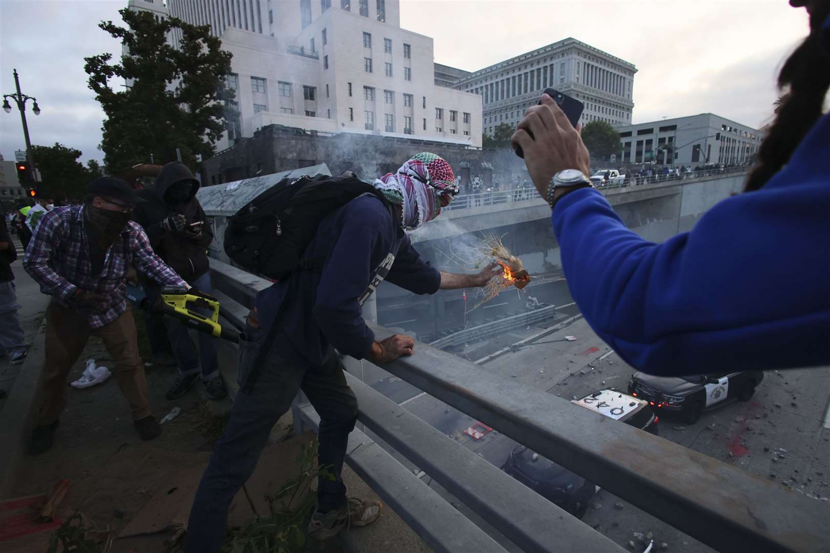 Protesters throw objects to the police vehicles on a Freeway near the Metropolitan Detention Centre in downtown Los Angeles (Ethan Swope/AP)