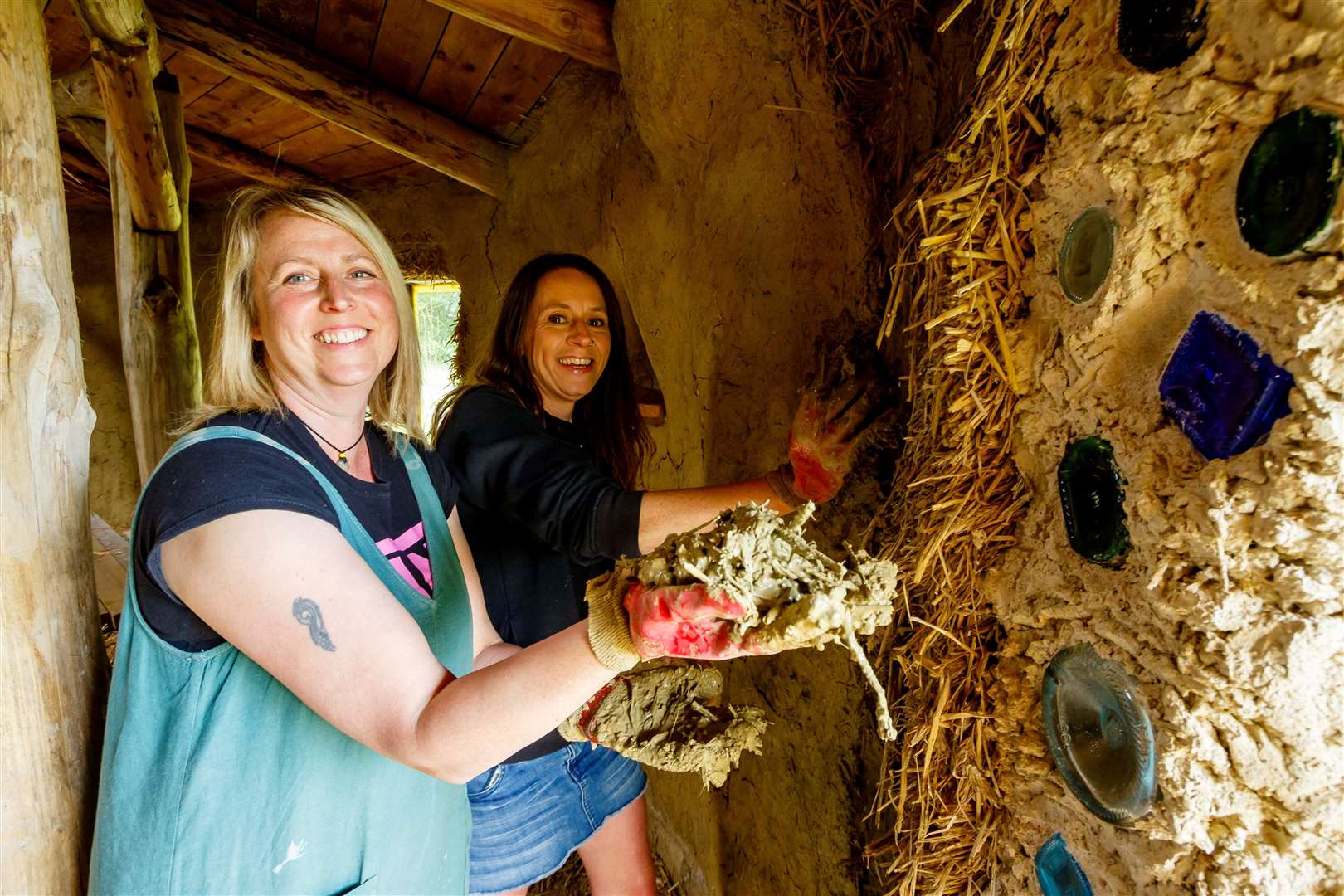 Lou Thompson and Ange Lamb showing how the cobbing is being applied to build the walls of Fox Wood Forest School’s roundhouse. Picture: Mark Bullimore