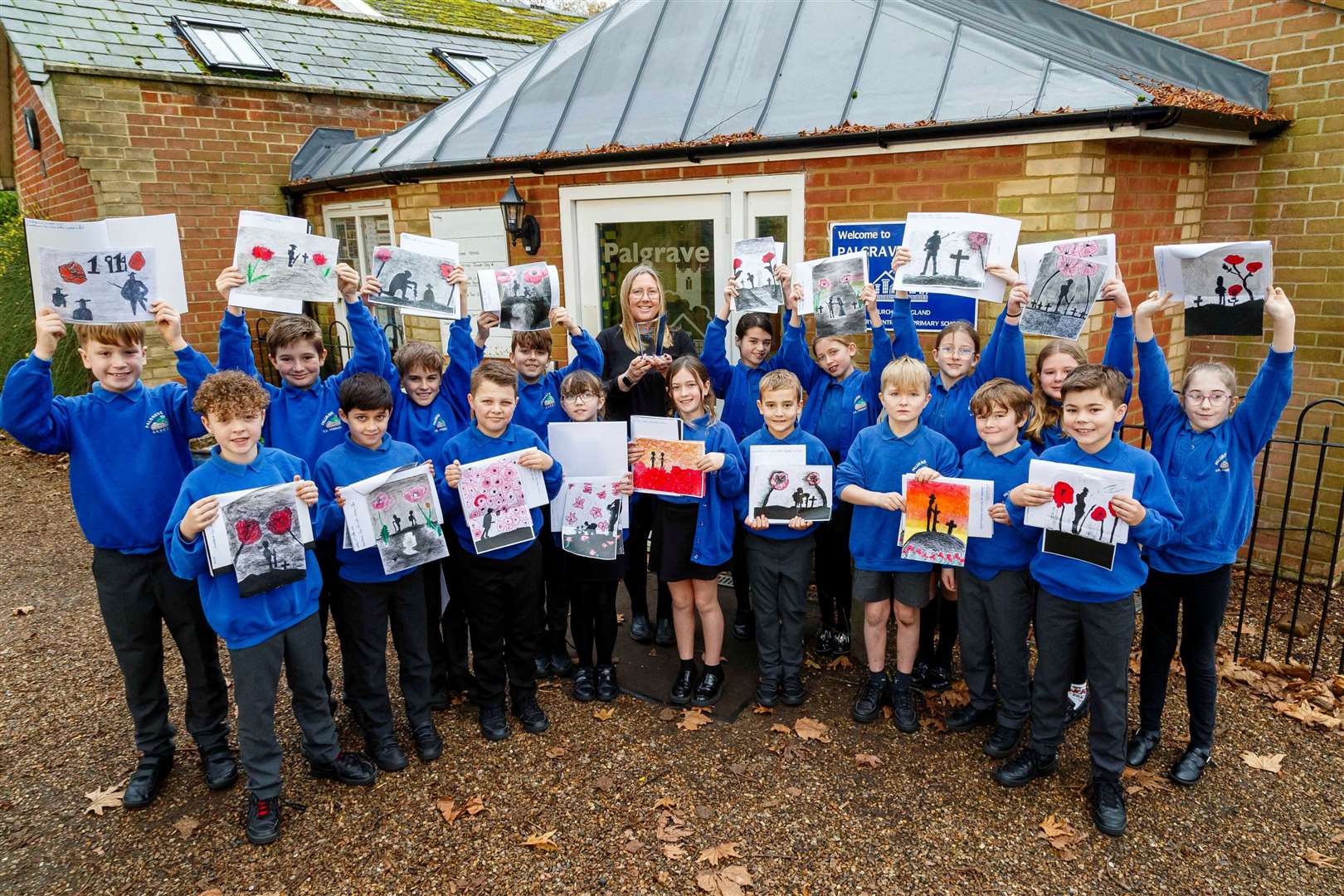 Julie Cook holds the trophy aloft, flanked by pupils with their artwork.Picture: Mark Bullimore