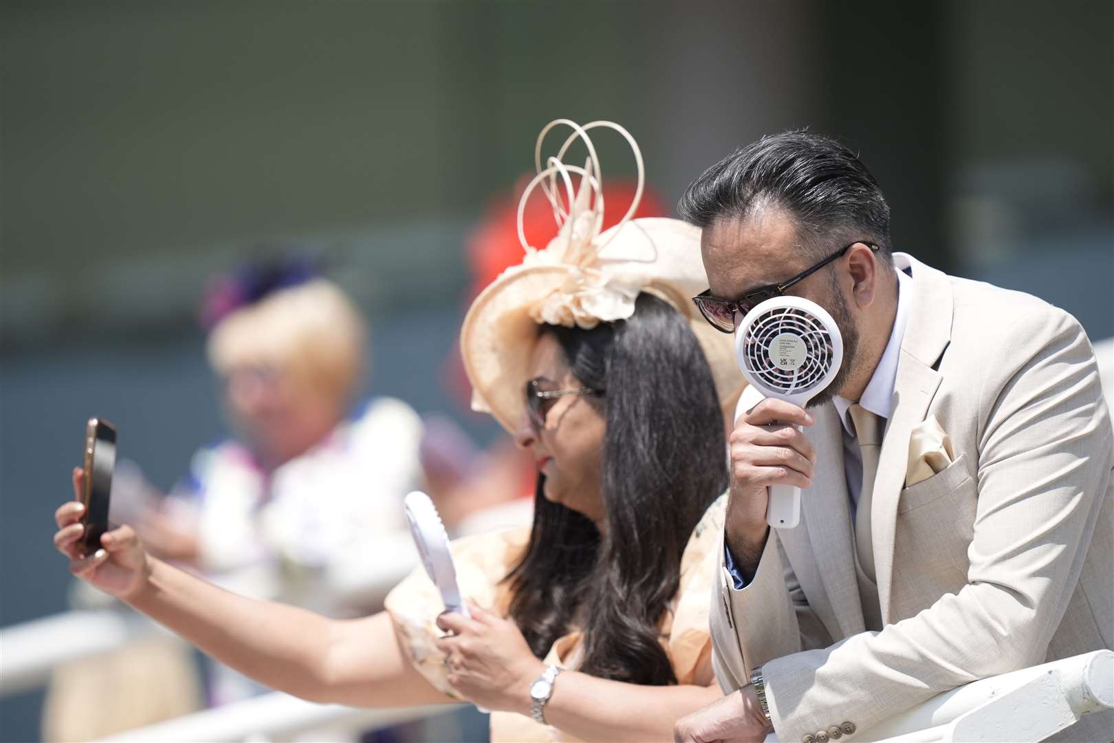 Racegoers using fans to cool themselves down on day three of Royal Ascot (Andrew Matthews/PA)