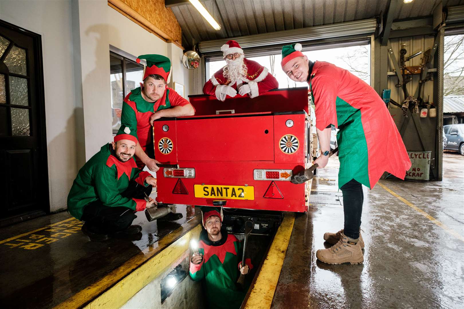 Garage owner Rob Vincent, second from left, with Ian Roper, Jack Adlard and Callum Sculfor working on the sleigh as Santa watches on. Picture: Nick Strugnell