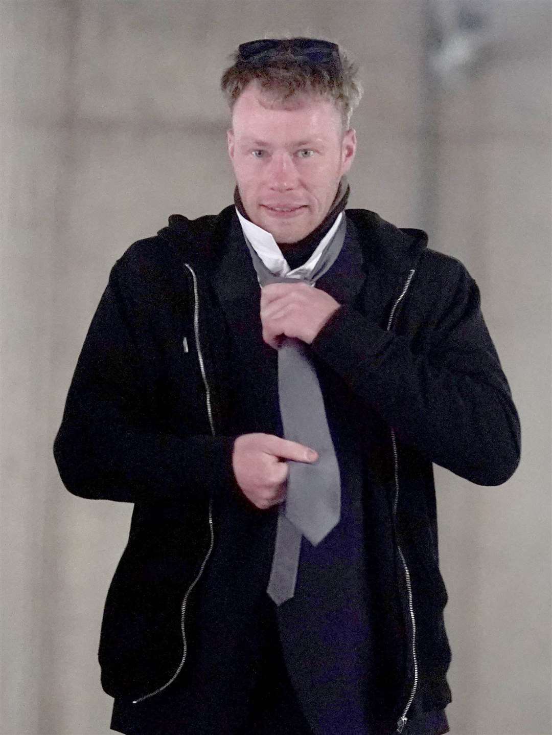 Adam Carruthers, 32, adjusts his clothing as he arrives to attend Newcastle Crown Court where he is accused of criminal damage after the felling of the Sycamore Gap tree (PA)