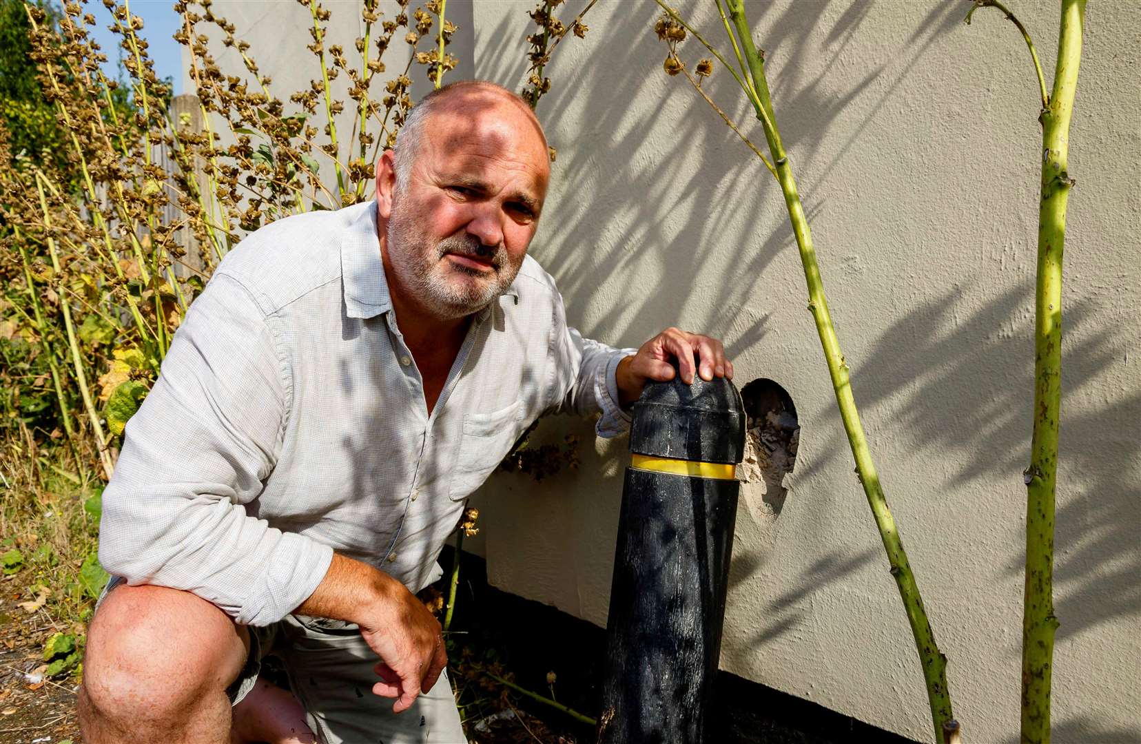 Justin showing the damage the plastic bollards have made to the side of his home. Picture: Mark Bullimore