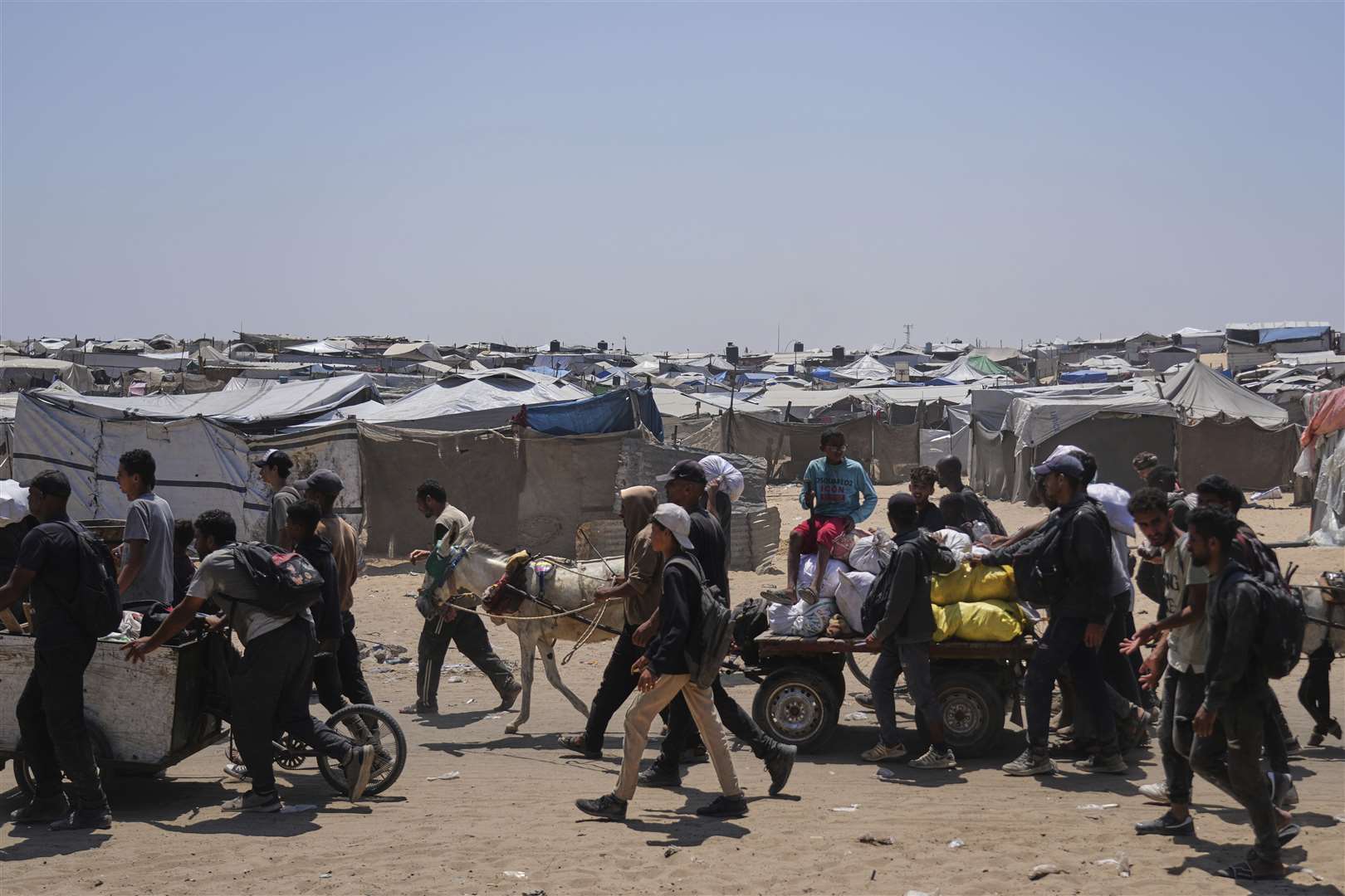 Palestinians carry bags containing food and humanitarian aid packages delivered by the Gaza Humanitarian Foundation, a US-backed organisation, in Rafah, southern Gaza Strip (Abdel Kareem Hana/AP)