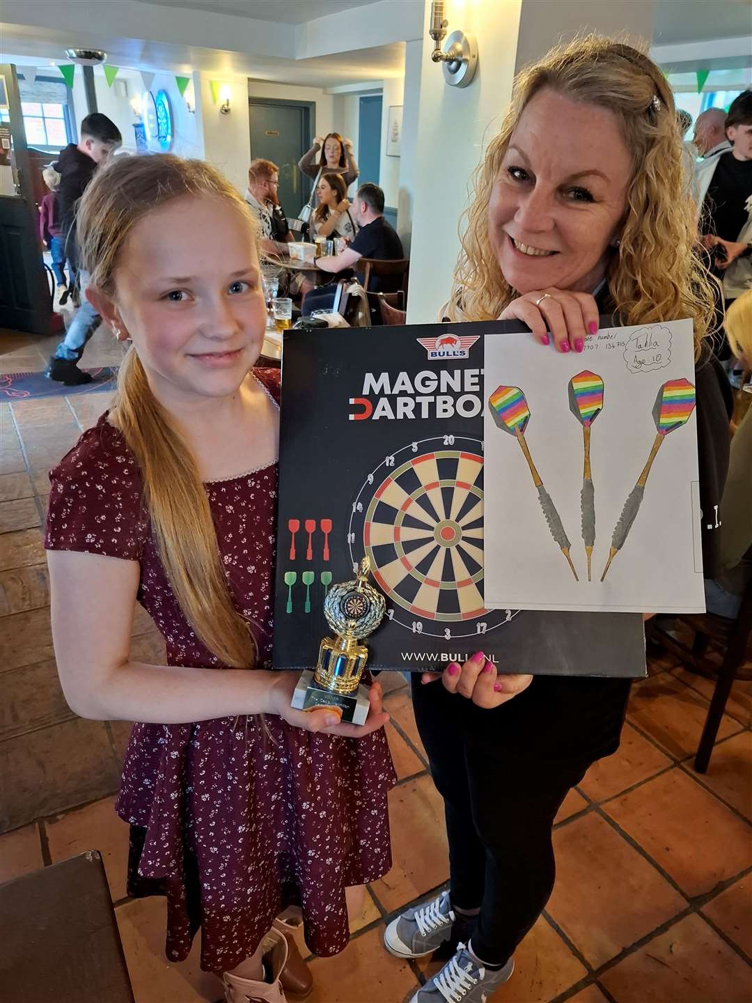 Tanya Heasley presents Tahlia aged 10, with her prize after winning the 'design darts flights' colouring competition.